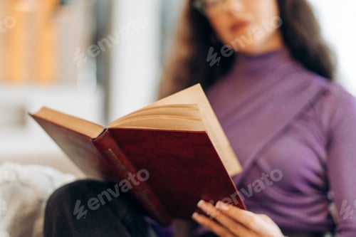 Preview: Beautiful woman reading interesting book at home, selective focus in hands