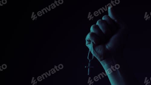 Preview: Praying with a rosary. hand of Catholic man with rosary on black background.