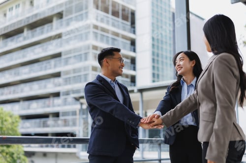 Preview: Business team joining hands celebrating success in front of office buildings