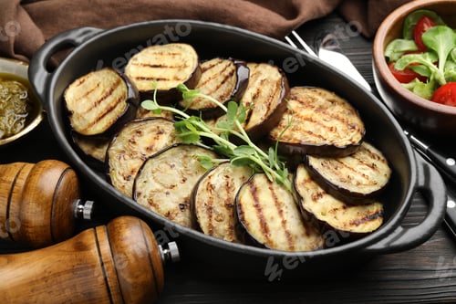 Preview: Grilled slices of eggplant with microgreens served on wooden table, closeup