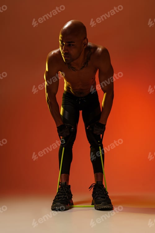 Preview: Sporty man performs exercises with expander on studio background. Strength and motivation