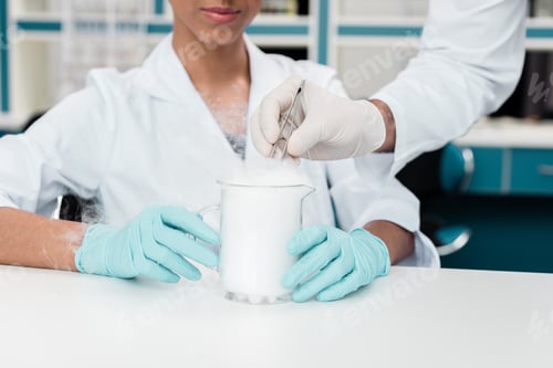 Preview: Cropped shot of colleagues in white coats working with reagent in chemical lab