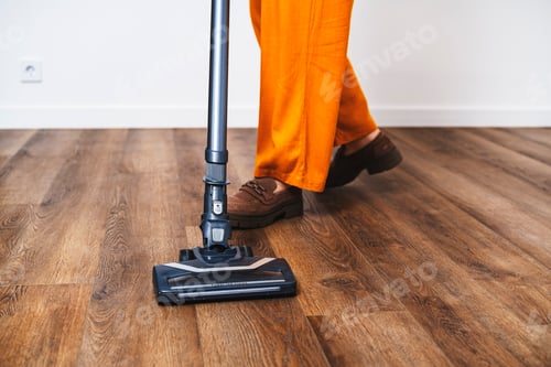 Preview: Woman using high tech vacuum cleaner brush on wooden surface. Close up of home cleaning