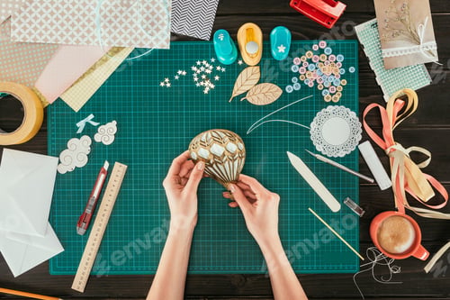 Preview: cropped image of designer making scrapbooking decoration for postcard in shape of balloon