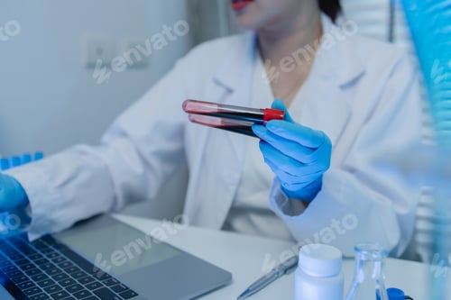 Preview: a female chemist is testing various liquid compounds in a lab