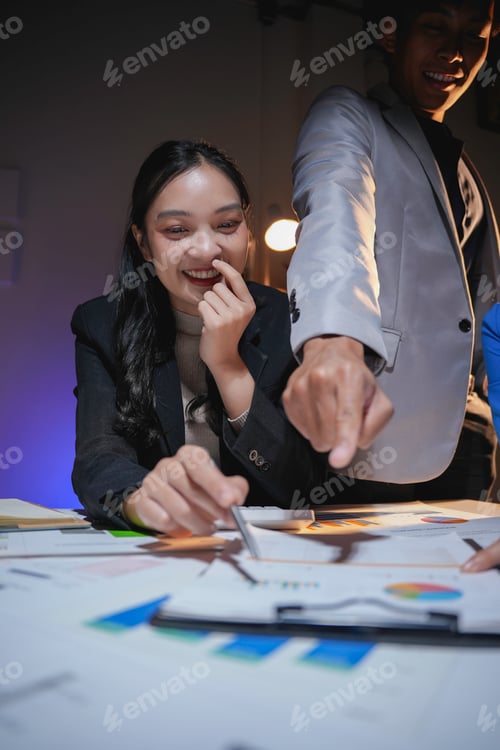 Preview: Business team working late and pointing at financial documents on table