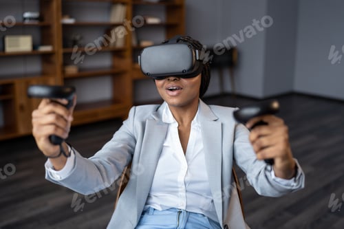 Preview: Excited businesswoman in virtual reality headset use joystick test VR goggles for gaming in office