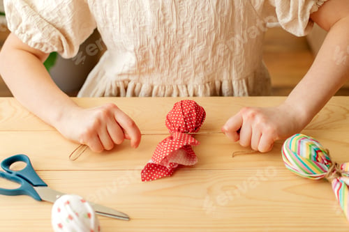 Preview: Close-up of a girl's hands at home making easter egg decorations in the shape of a rabbit from