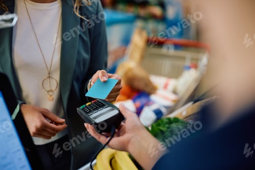 Preview: Close up of woman using credit card while buying in supermarket.