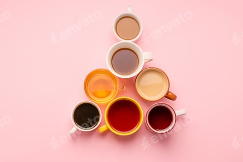 Preview: Mugs and glasses with various traditional drinks stand with a pyramid on a pink background. Drinks