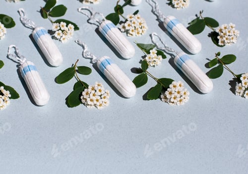 Preview: Medical female tampon and white flowers on a blue background. Hygienic white tampon for women.