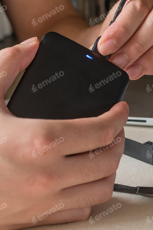 Preview: Male hand connecting hard drive with USB cable to laptop computer