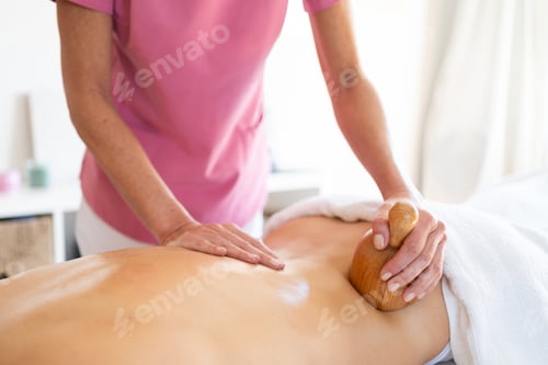 Preview: Crop masseur doing massage to client with wooden therapy tools in physiotherapy clinic
