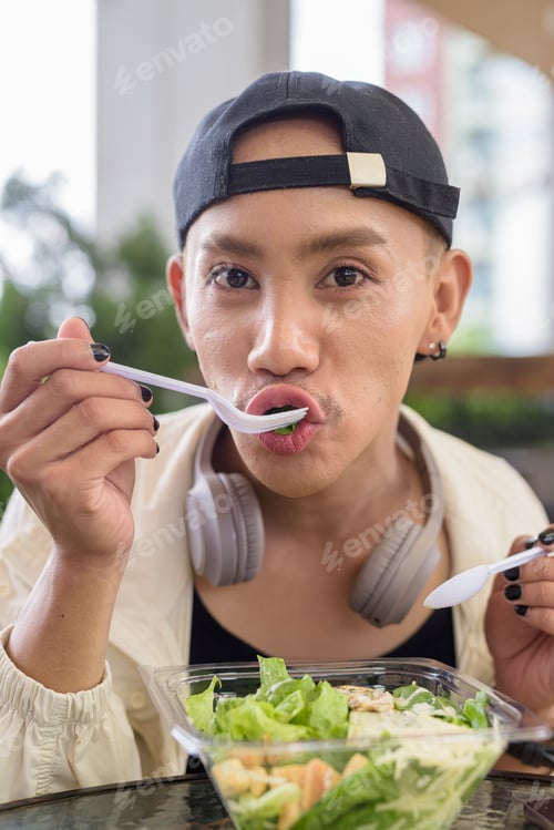 Preview: Nonbinary person eating healthy caesar salad outdoors