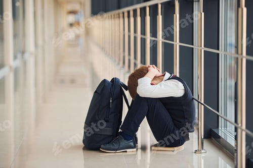 Preview: Boy in uniform sitting alone with feeling sad at school. Conception of harassment