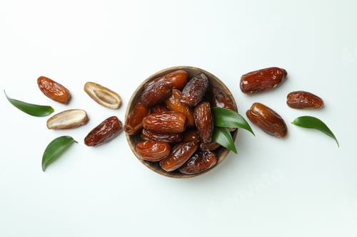 Preview: Bowl of dried dates with leaves on white background