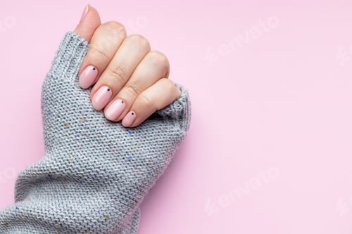 Preview: Female hand with trendy beautiful manicure - pink nude nails with black small dots