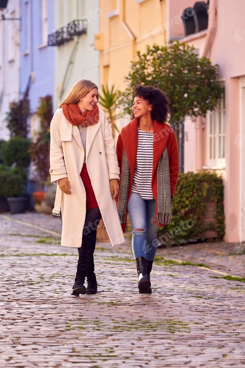 Preview: Woman Meeting Female Friend Walking Along Residential City Street In Fall Or Winter