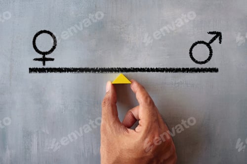Preview: Hand holding wooden triangle with gender icon on balancing scale.