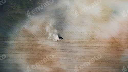 Preview: Tractor cultivating field at spring, aerial top view, tilling soil