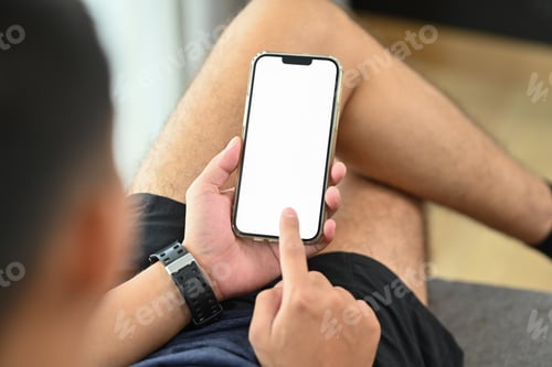 Preview: Close up young man sitting on couch typing message and chatting with friends on mobile phone