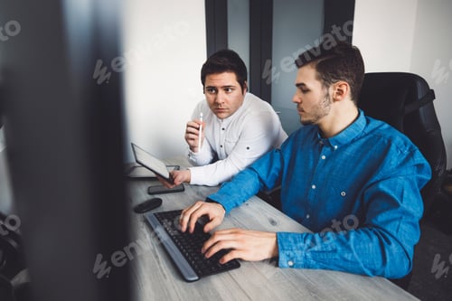 Preview: Two young caucasian programmers working on desktop computers in the office developing a new video