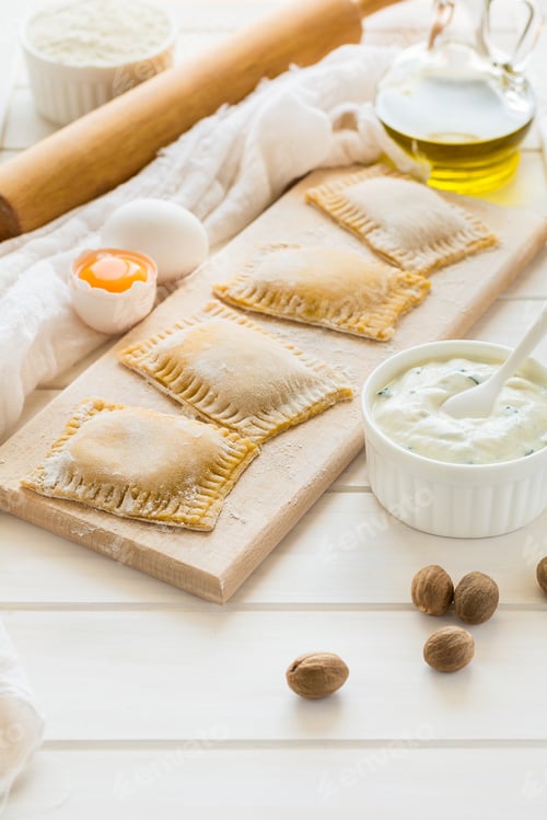 Preview: Fresh ravioli with spinach and ricotta waiting to be cooked on wooden table. Selective focus