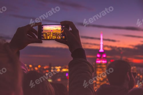 Preview: Hands holding up phone to take photo of Empire State Building at night in New York travel experience