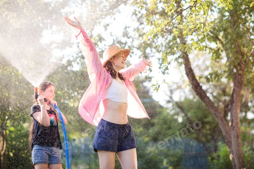 Preview: happy family. child uses hose to water plants in garden in Sunny hot summer day. kids fun.