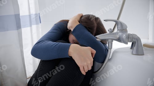 Preview: Young woman hiding in bath and covering her head with hands while beaing victim of earthquake