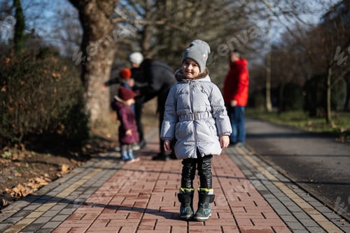 Preview: Baby girl in jacket stand on the way at park.