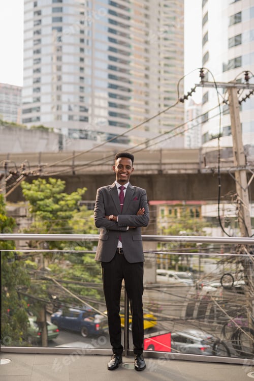 Preview: Portrait of handsome young African businessman outdoors in city