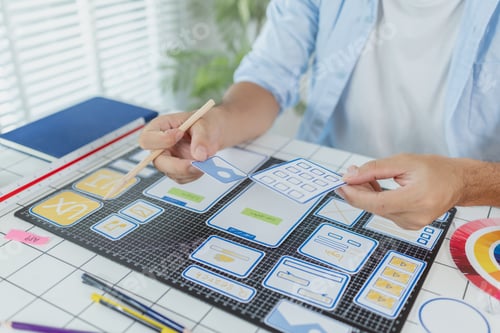 Preview: A designer is developing UX UI layouts, reviewing mobile app prototypes