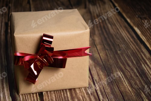 Preview: Wrapped Present with Red Ribbon on Wooden Surface