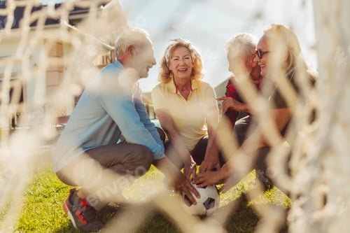 Preview: Senior friends holding a soccer ball before playing football in the backyard