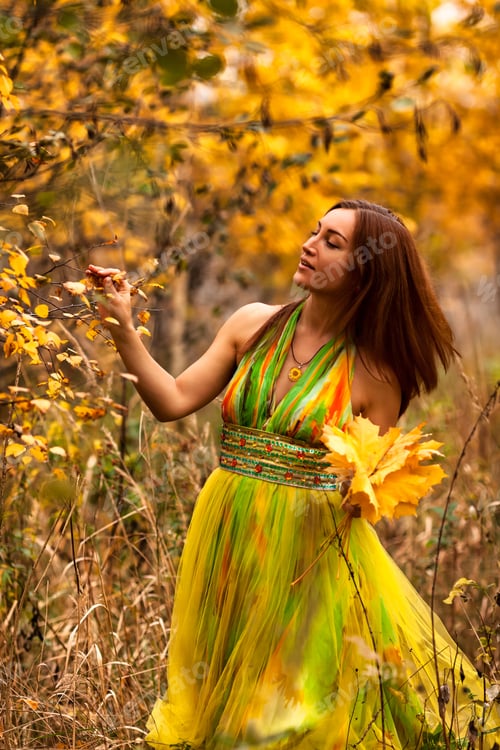 Preview: Captivating Woman in Vibrant Gown Enjoys Autumn Foliage While Collecting Colorful Leaves