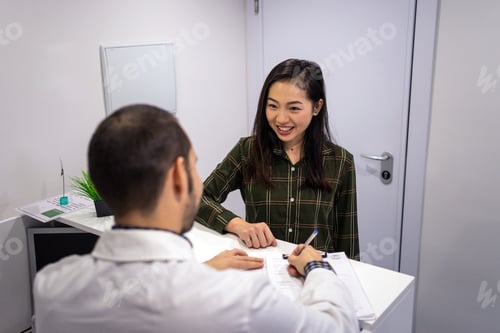Preview: Male doctor talking with patient and filling out papers
