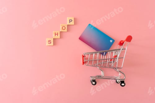 Preview: shopping cart with credit cart and word shop on pink background
