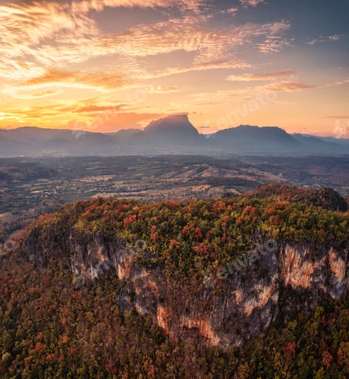 Preview: Sunset over mountain range with colorful autumn forest on hill in countryside