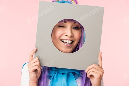 Preview: Smiling asian anime girl holding cardboard isolated on pink
