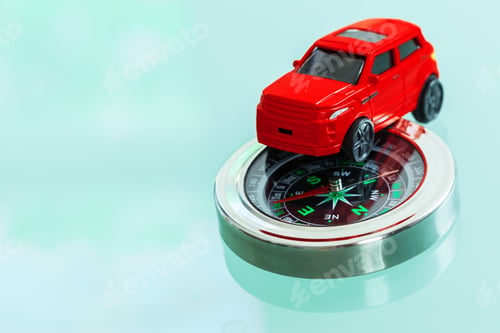 Preview: Small red toy car sits on a compass with a clear background and reflective surface