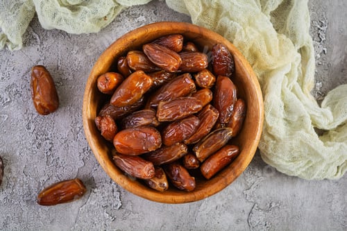 Preview: Dried date fruit in bowl on wooden background. Delicious dates fruit