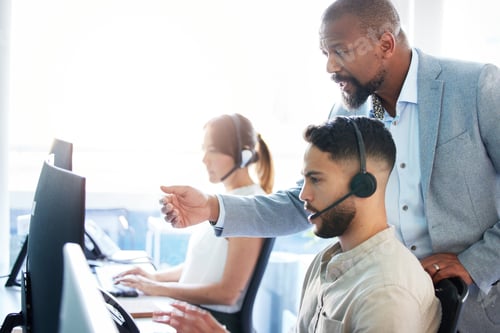 Preview: Shot of a mature businessman standing and helping his call centre agents in the office
