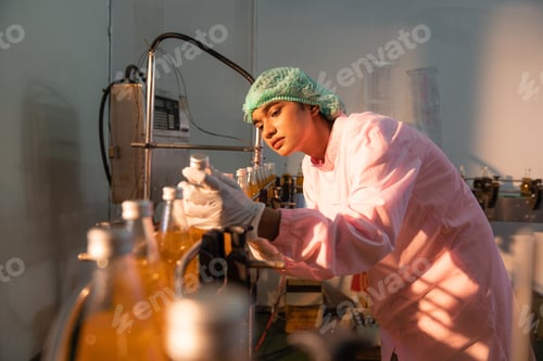 Preview: Woman worker quality control a fruit drink factory in glass.