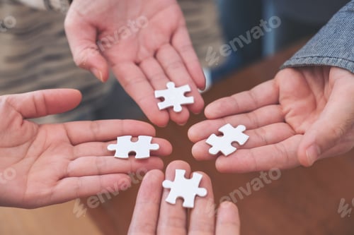 Preview: Closeup image of many people hands holding and putting a piece of white jigsaw puzzle together