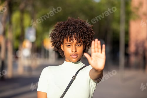 Preview: Young woman making a stop gesture with the raised palm of her hand