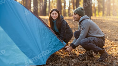 Preview: Active couple settle camping tent in the middle of forest
