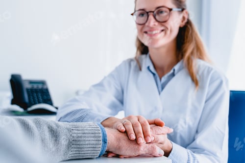 Preview: Smiling woman doctor in glasses holding her patient`s hand to support him
