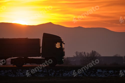 Preview: Semi-truck with cargo trailer driving on highway hauling goods in evening.
