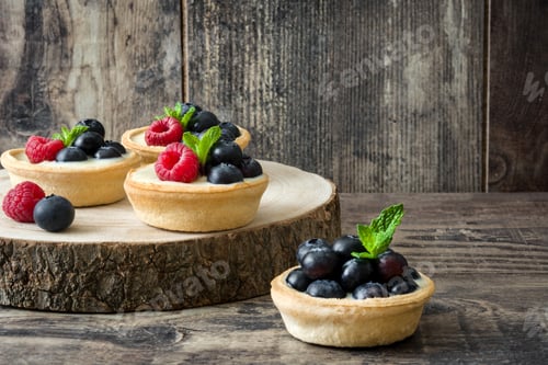 Preview: Delicious mini tarts with fresh berries and mint on rustic wooden background